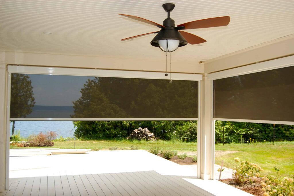 Interior of porch with a ceiling fan and motorized mesh solar shades