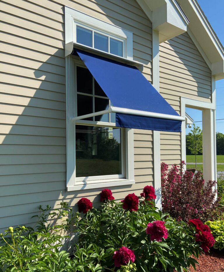 A blue window awning on a tan house providing shade.