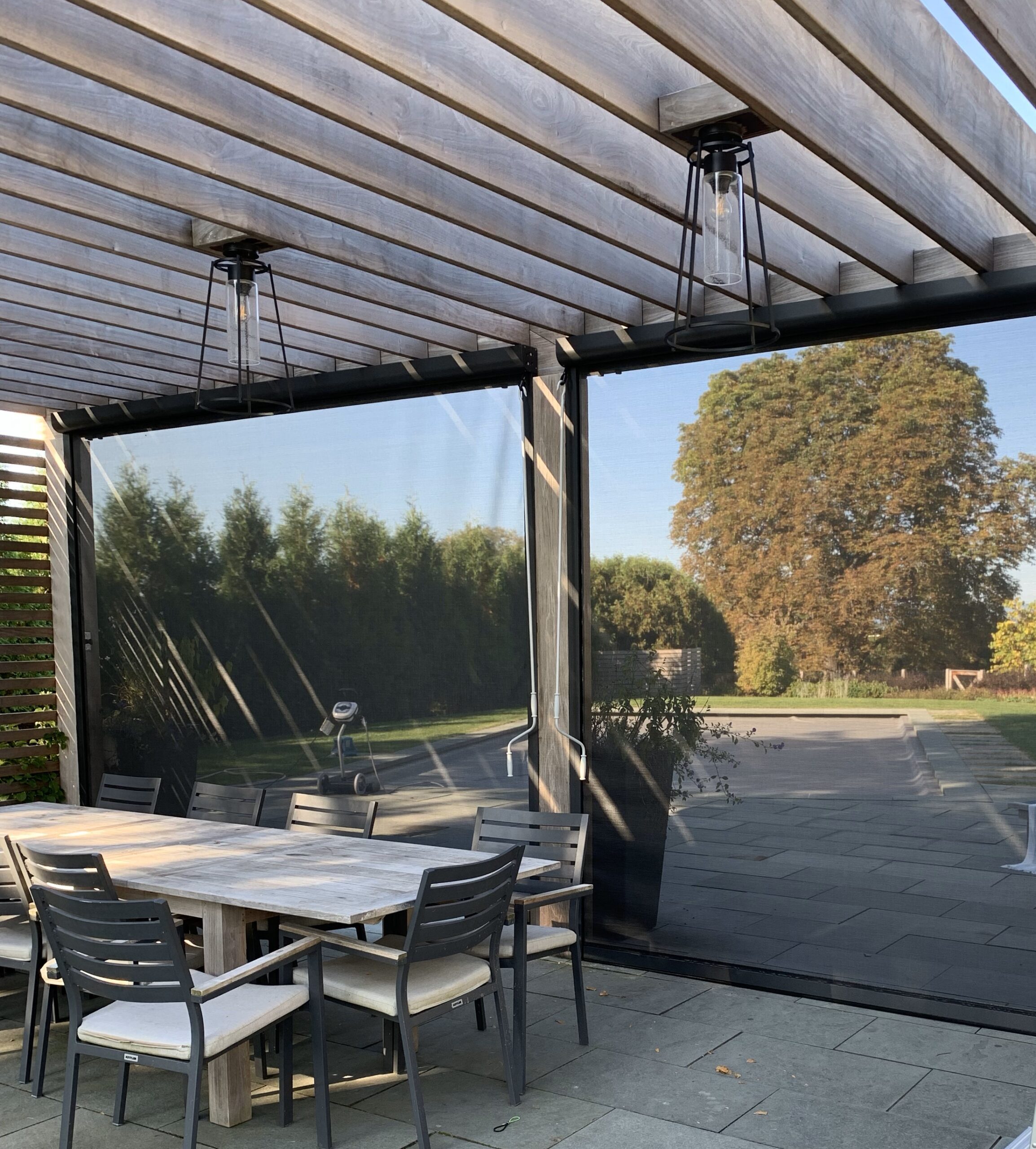 A pergola with exterior solar screens installed with mesh fabric.