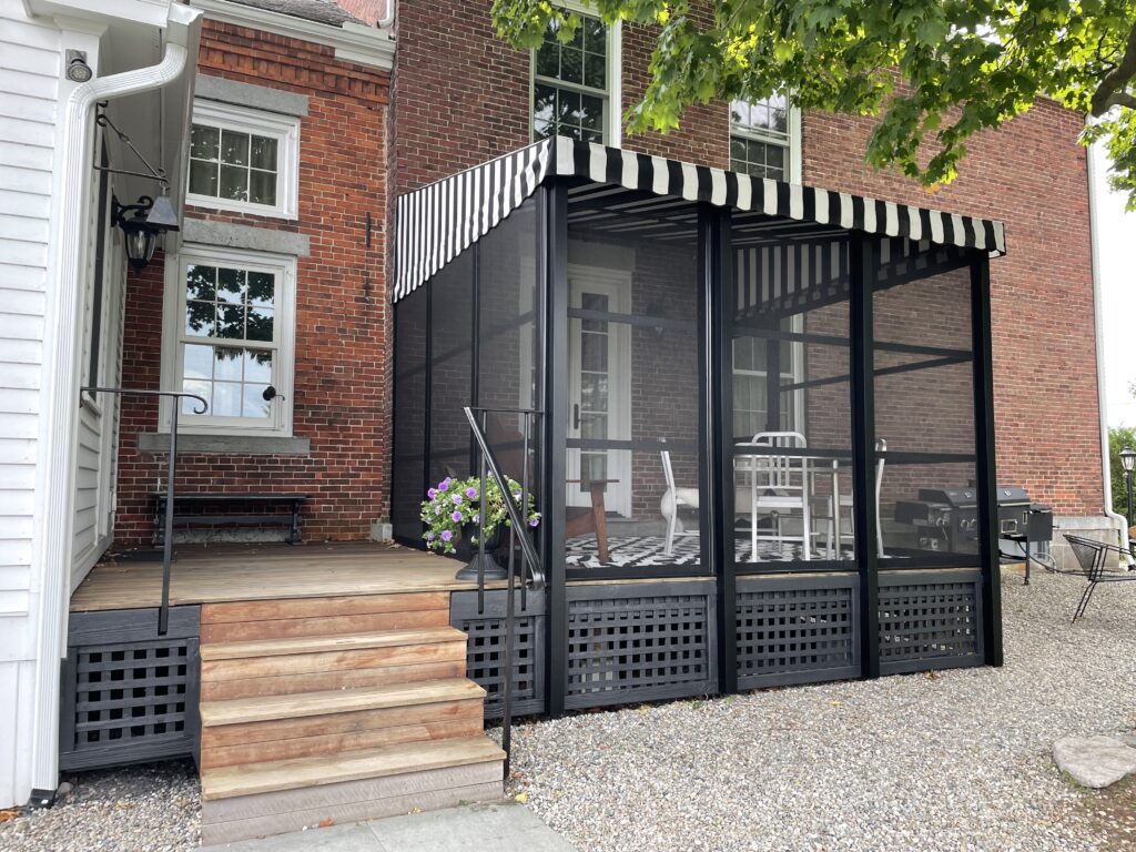 Bistro style deck canopy with black and white fabric on historic brick home.