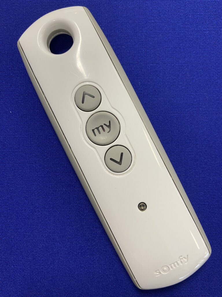 Photo of Somfy awning remote on a blue background.
